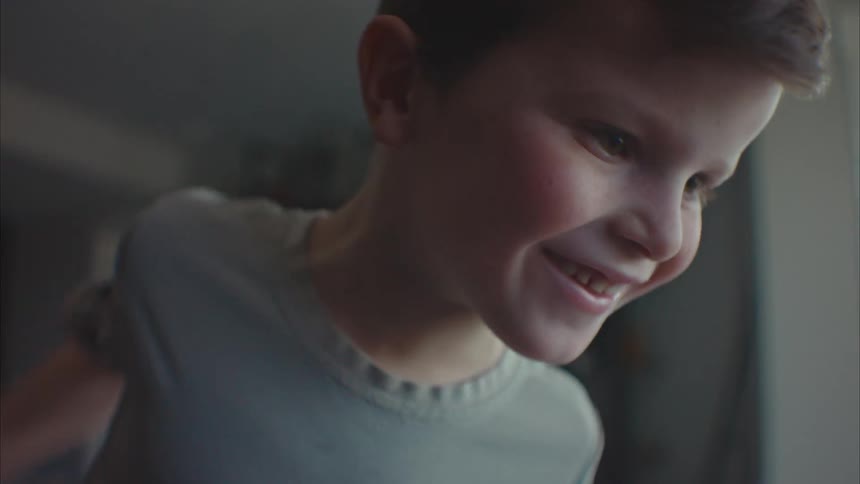 A little boy is looking down and moving and then he becomes happy and raises his arms to celebrate