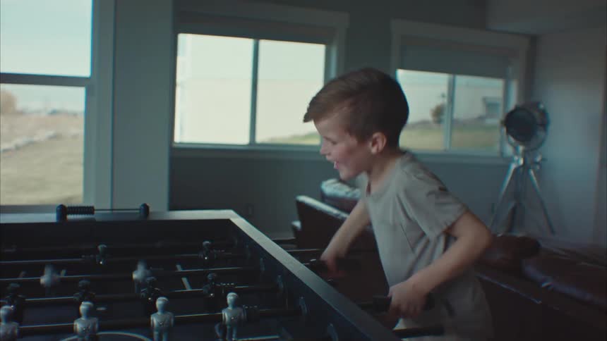 A little boy and a little girl are playing foosball and the boy is smiling