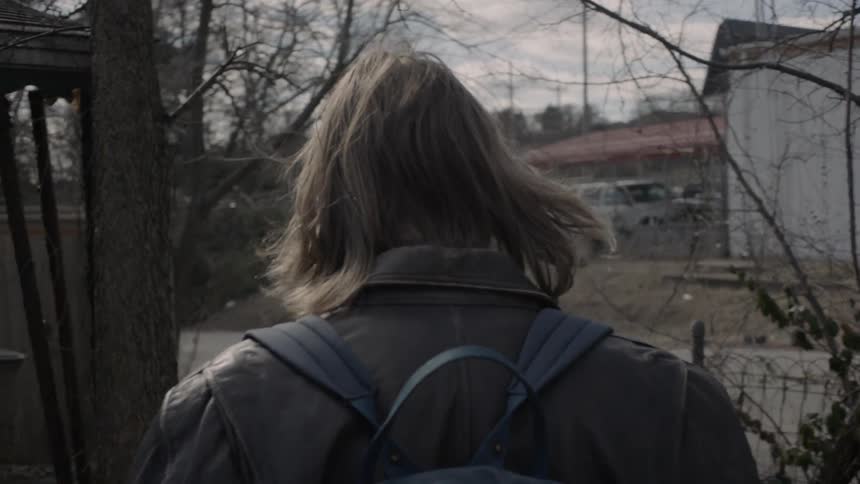 Someone with a backpack is outside in a alley