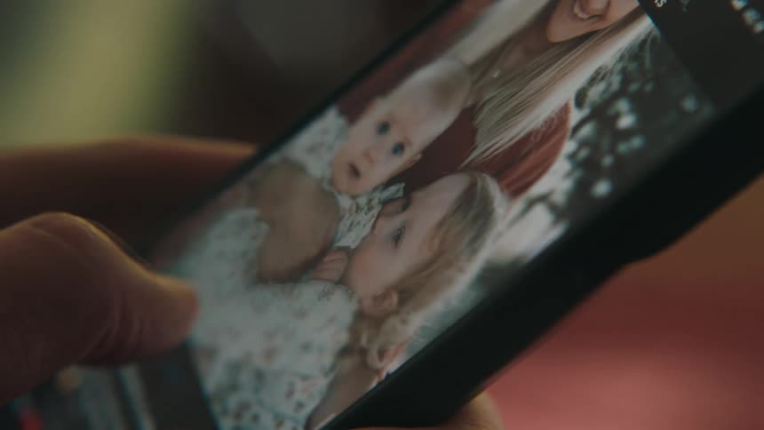 A person scrolls through pictures of a woman and two kids
