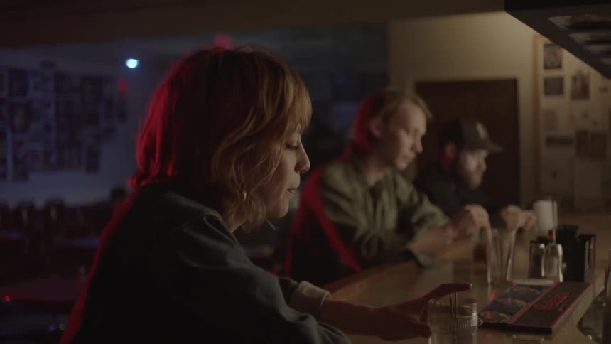 A woman is sitting at a bar stirring her drink