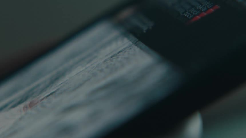 A human finger dragging a cell phone screen upwards and is scrolling through several photos on the screen