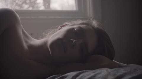 A woman is laying in bed looking worried