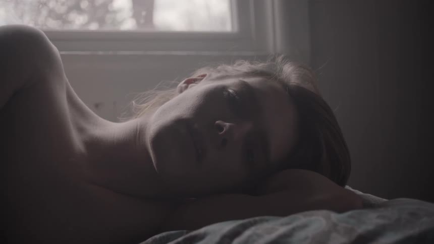 A woman is laying in bed looking worried