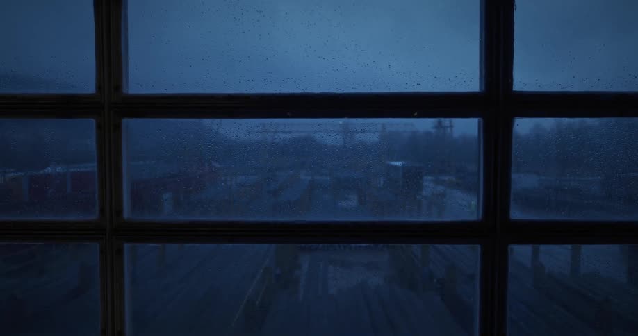 Window shows factory loading center on a rainy day