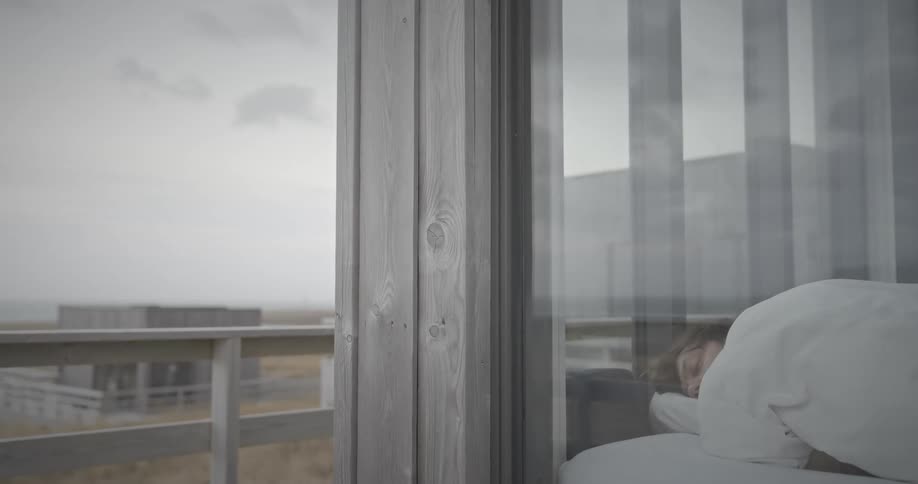 A person sleeping in a bed viewed from a balcony