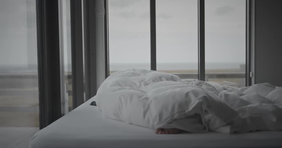 A person sleeping in a bed wrapped in a white blanket