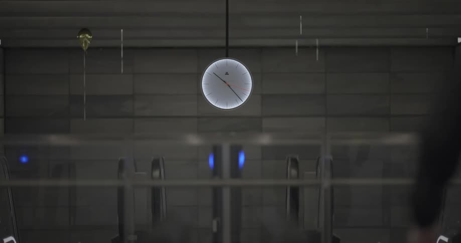 View of a central clock facing escalators in a train terminal
