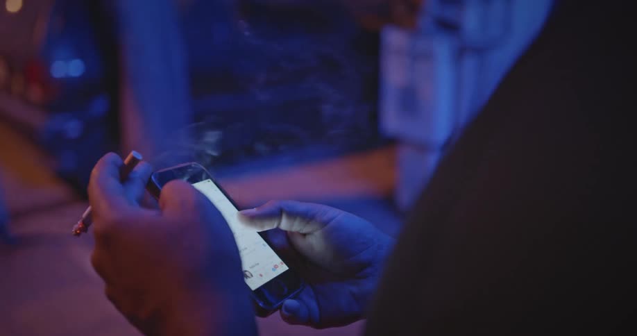 A person using a cell phone while holding a cigarette