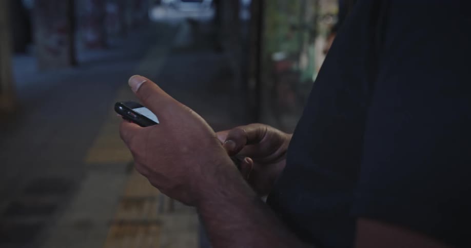 A person typing on their cell phone outdoors in the city