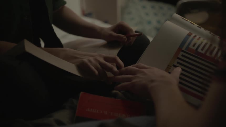 Two teenagers touch fingers as they are studying in a bedroom
