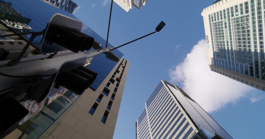 A utility pole filled with traffic signs at a corner of a tower block