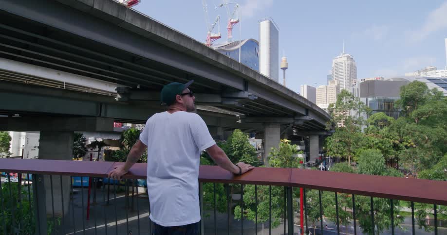 A man leans on a railing in a city