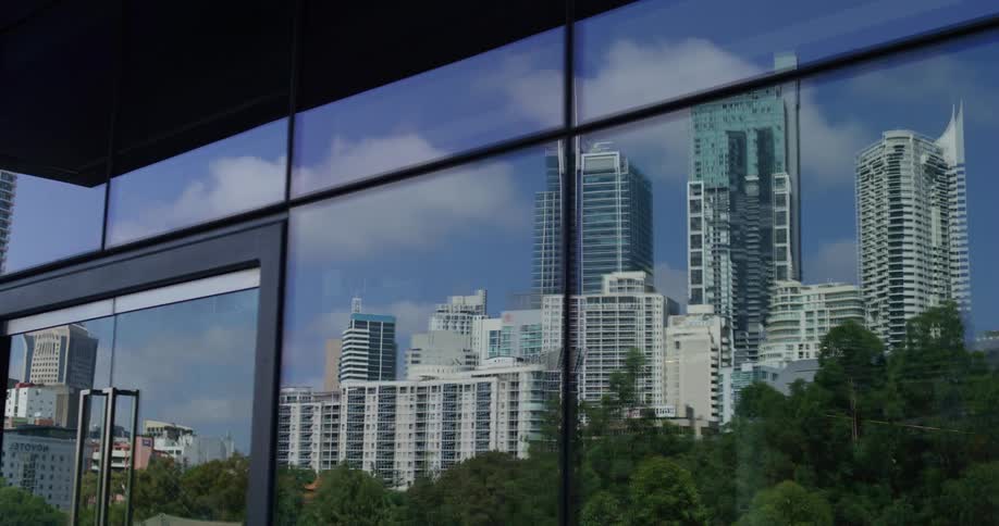 The reflection of many tall buildings in a glass wall with doors