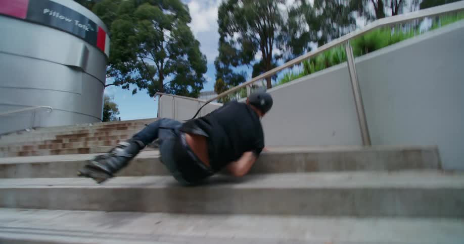 Man performing risky maneuver on handrail with roller skates and falling on stairs