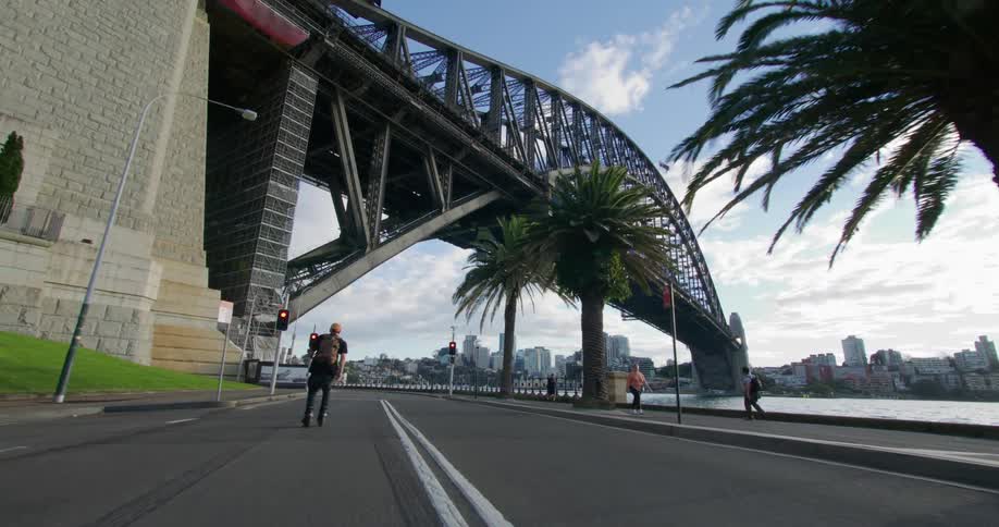 A person riding a roller on an asphalt street under a bridge
