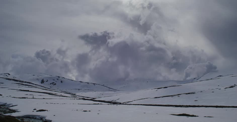 The clouds flow over the snow covered mountains