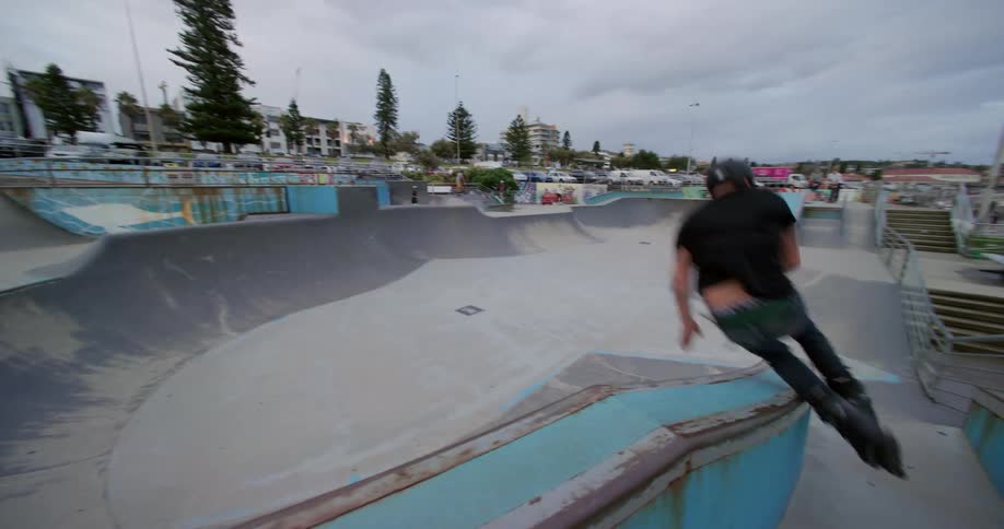 A man on roller skates attempts to grind a wall and falls