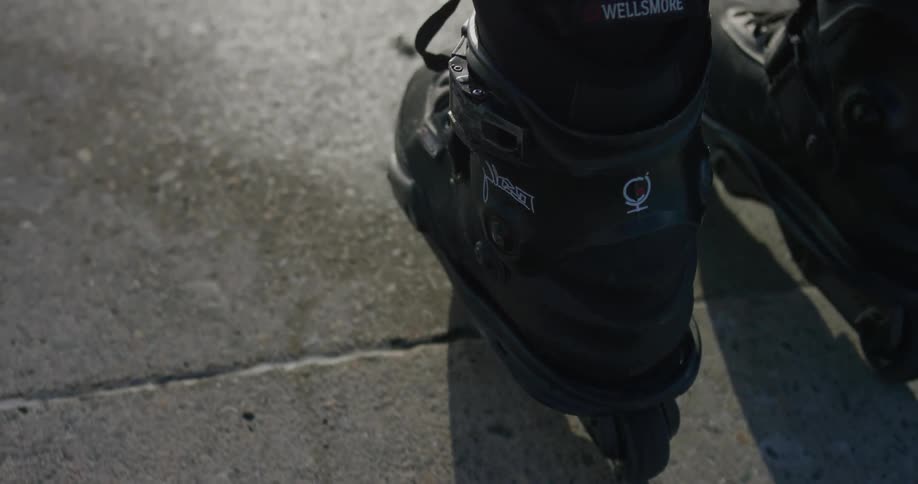 A person wearing inline skates moves over pavement