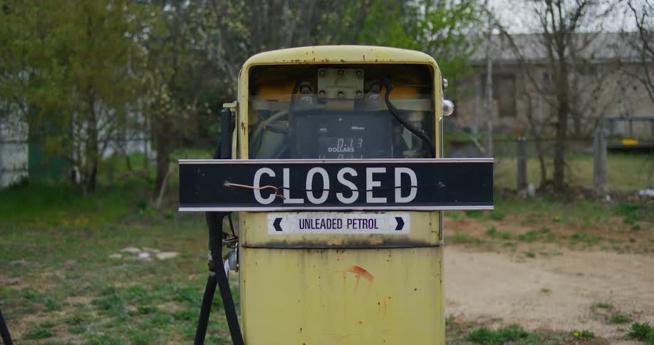 A derelict gas pump is partly disassembled and has a closed sign on it