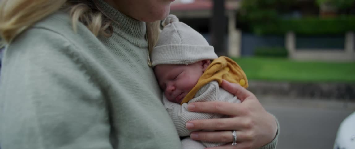 Mother carrying her newborn baby on her lap while walking down the street