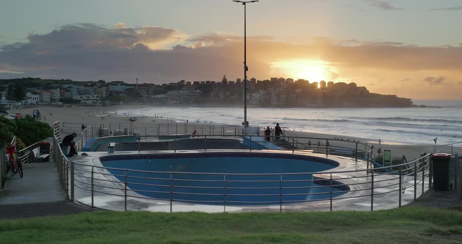 Skatepark behind railing near beach at sunset