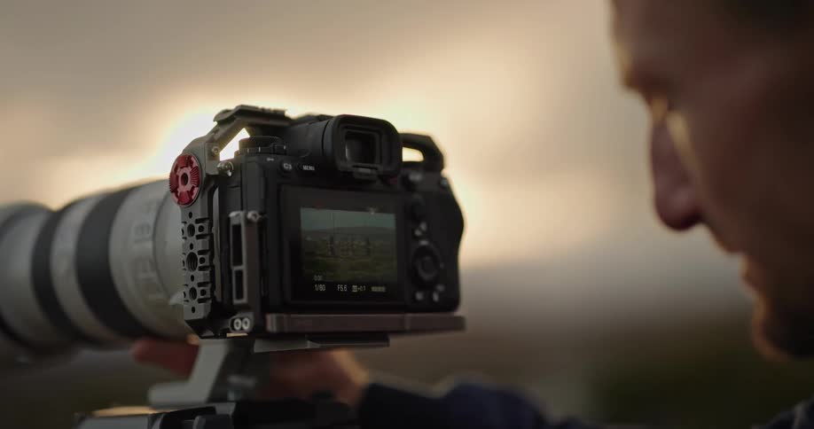 A male photographer sets up his camera to capture an image while outdoors