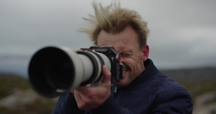 Professional photographer man taking photos with his camera with zoom lens in a windy outdoor environment in nature