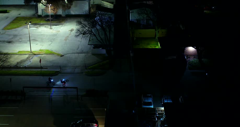 A couple of motorcycles riding on a town street at night