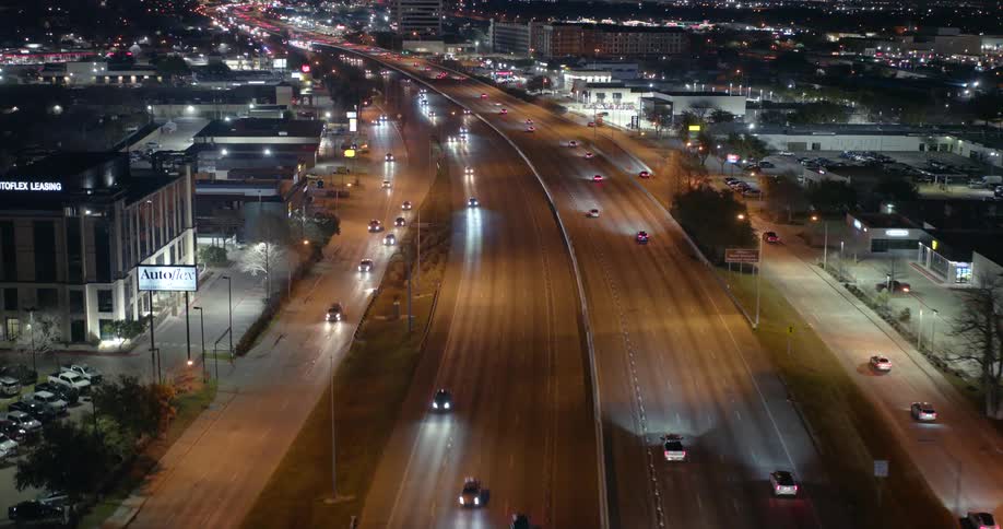 Aerial panorama of a road with a flow of vehicle traffic at night in the middle of a city