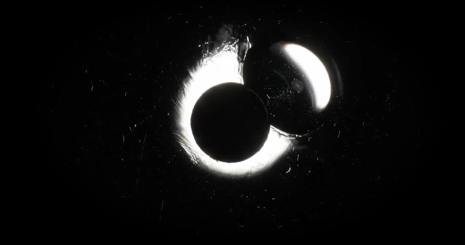 Extreme closeup and a bright abstract bubble dissolving in slow motion on a black background