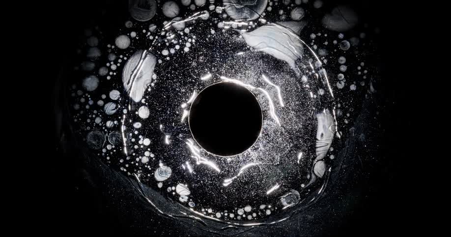 A black circular element attracting several white liquidshaped elements surrounding it