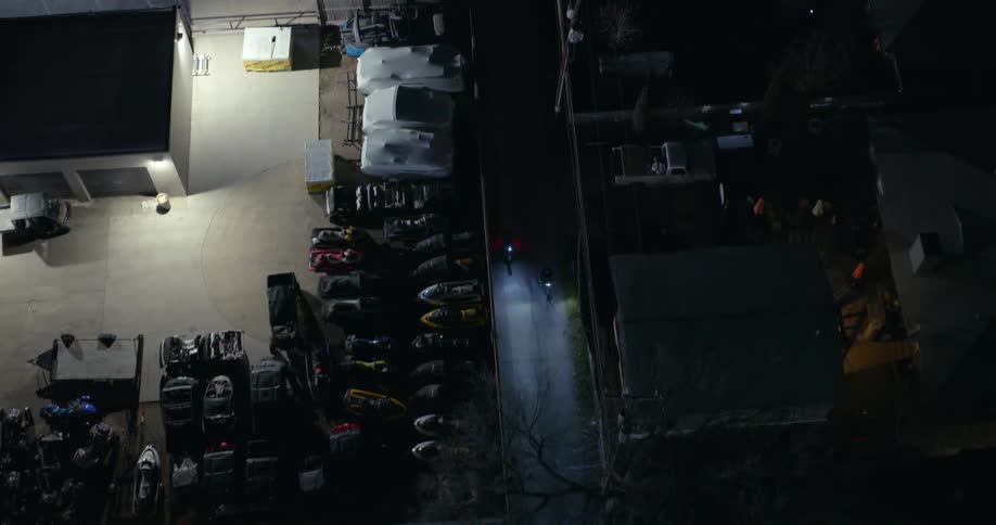 Aerial view of two motorcycles with headlights driving through a parking area at night