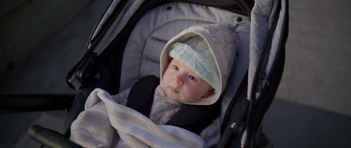 A baby pushed down a walk in a stroller
