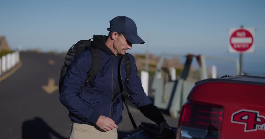 Photographer picks up tripod then closes tailgate of truck parked on roadside