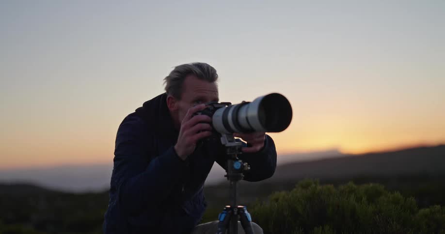 A man in nature looks through a camera