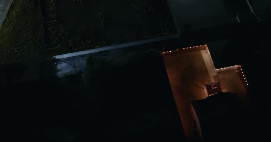 Aerial view of two people cycling in an alley and a residential neighborhood at night