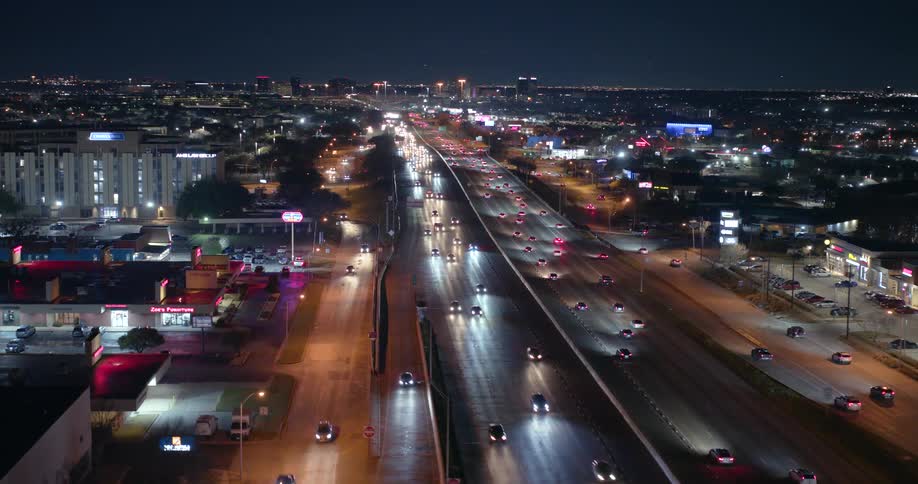 Traffic flows along multilaned controlled access freeway through the city at night