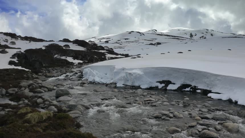 Aerial of a river running down a mountain during freezing winter