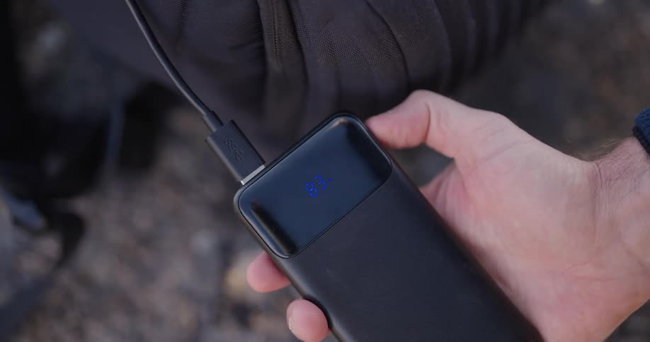 A person presses the button on their portable battery charger