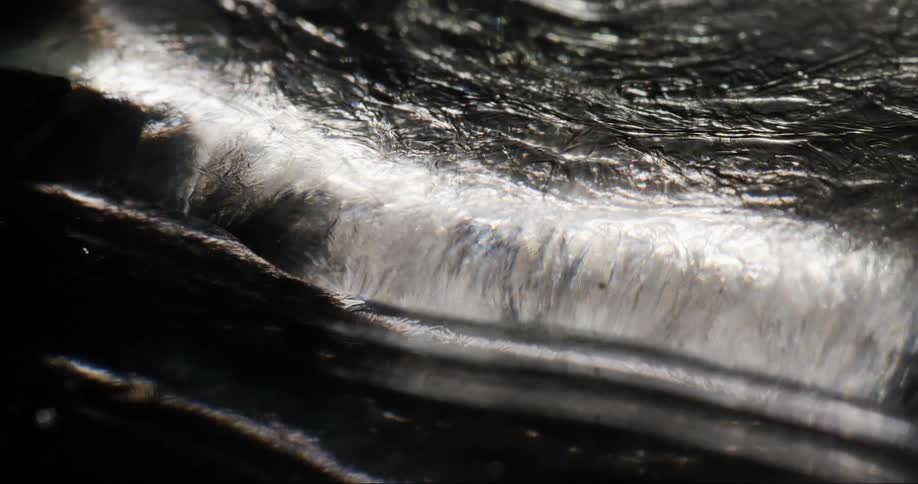 Light reflects off the moving silver liquid