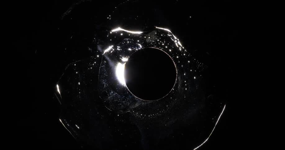 A dark circle inside a shimmering oily liquid