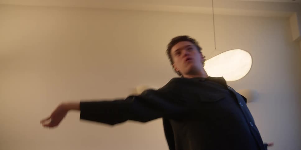 A young male dancer practicing his arm and body movements and technique in a city apartment private studio.