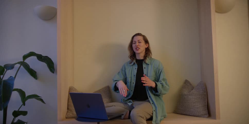 A female dance instructor sitting in front of a laptop coaching her young male student on his choreography technique.