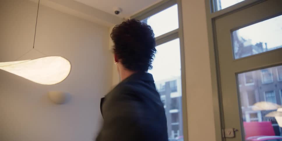 Point of view of a choreographer teaching a young man dance techniques and moves in a city apartment studio.