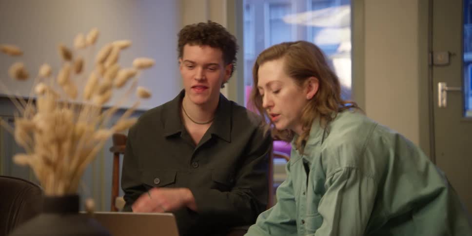 An experienced female dance teacher viewing choreography on a laptop with her young male student, then discussing and practicing the arm movements they are seeing.