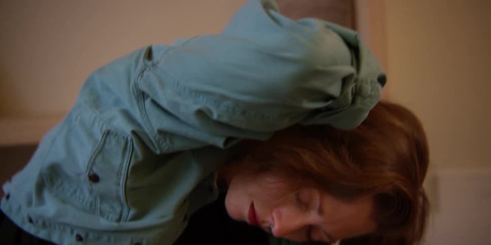 An adult woman stretching her arms and neck on the floor in her home