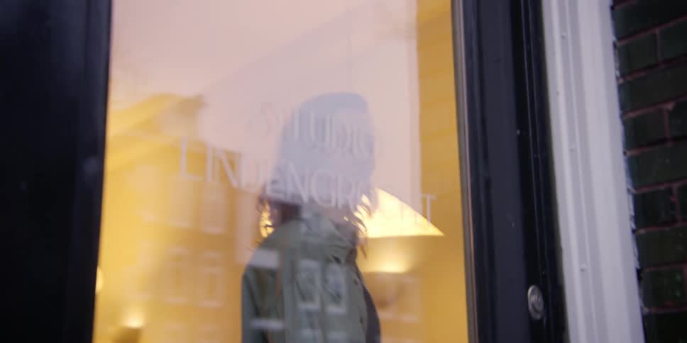 A man is greeting at the shop door by a woman and they hug
