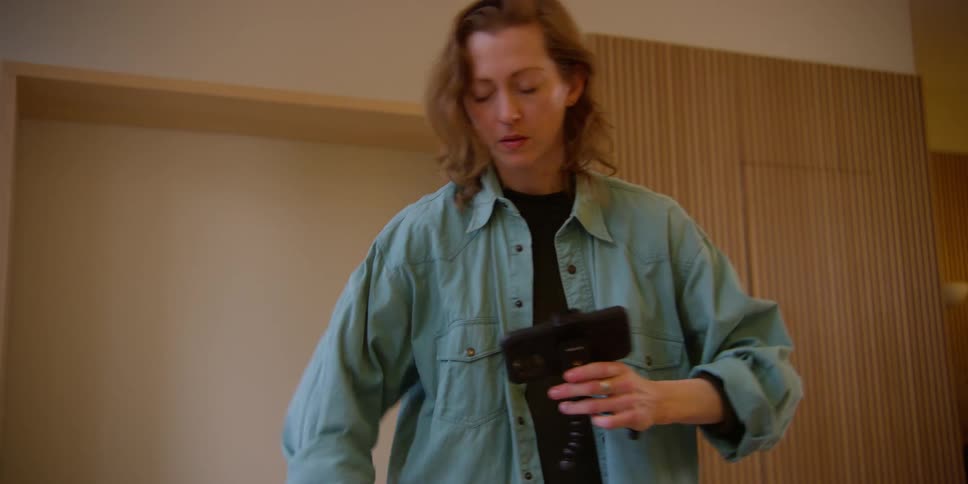 A female dancer watches the recording she just made on her smartphone and practices her arm movements with phone in hand