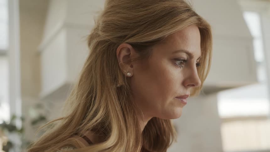 A woman in profile looking at a computer in a bright sunny home